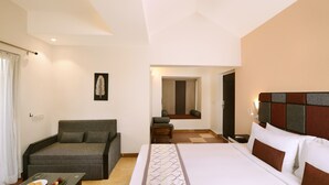 A hotel room with a bed, a sofa, a small table with fruits, and a wall-mounted artwork. - Sterling Kanha (Bichhiya)