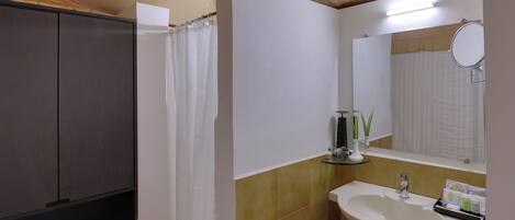 A bathroom with a shower, a sink, and a mirror.