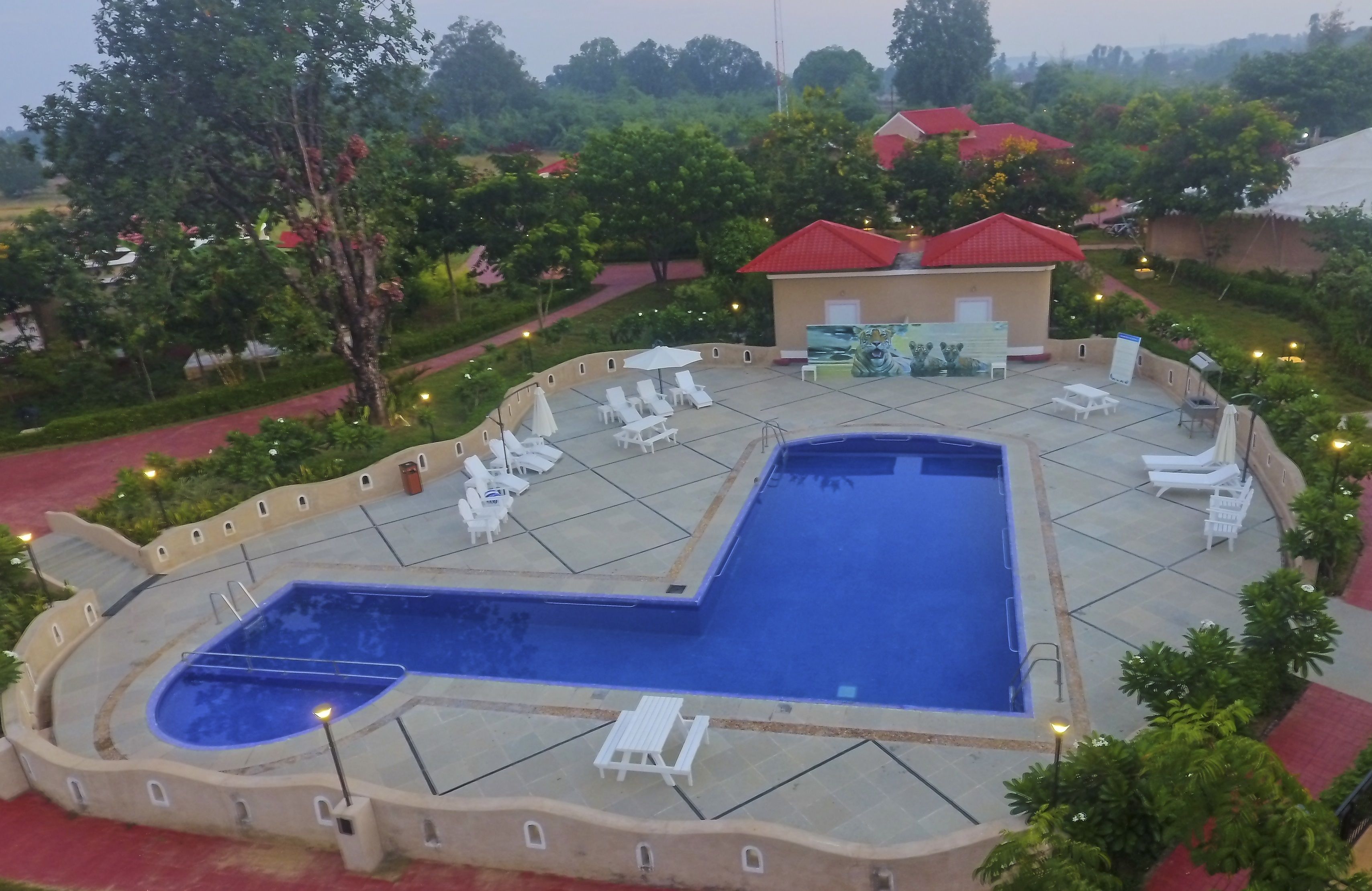 A pool area with lounge chairs and a small building with a red roof.
