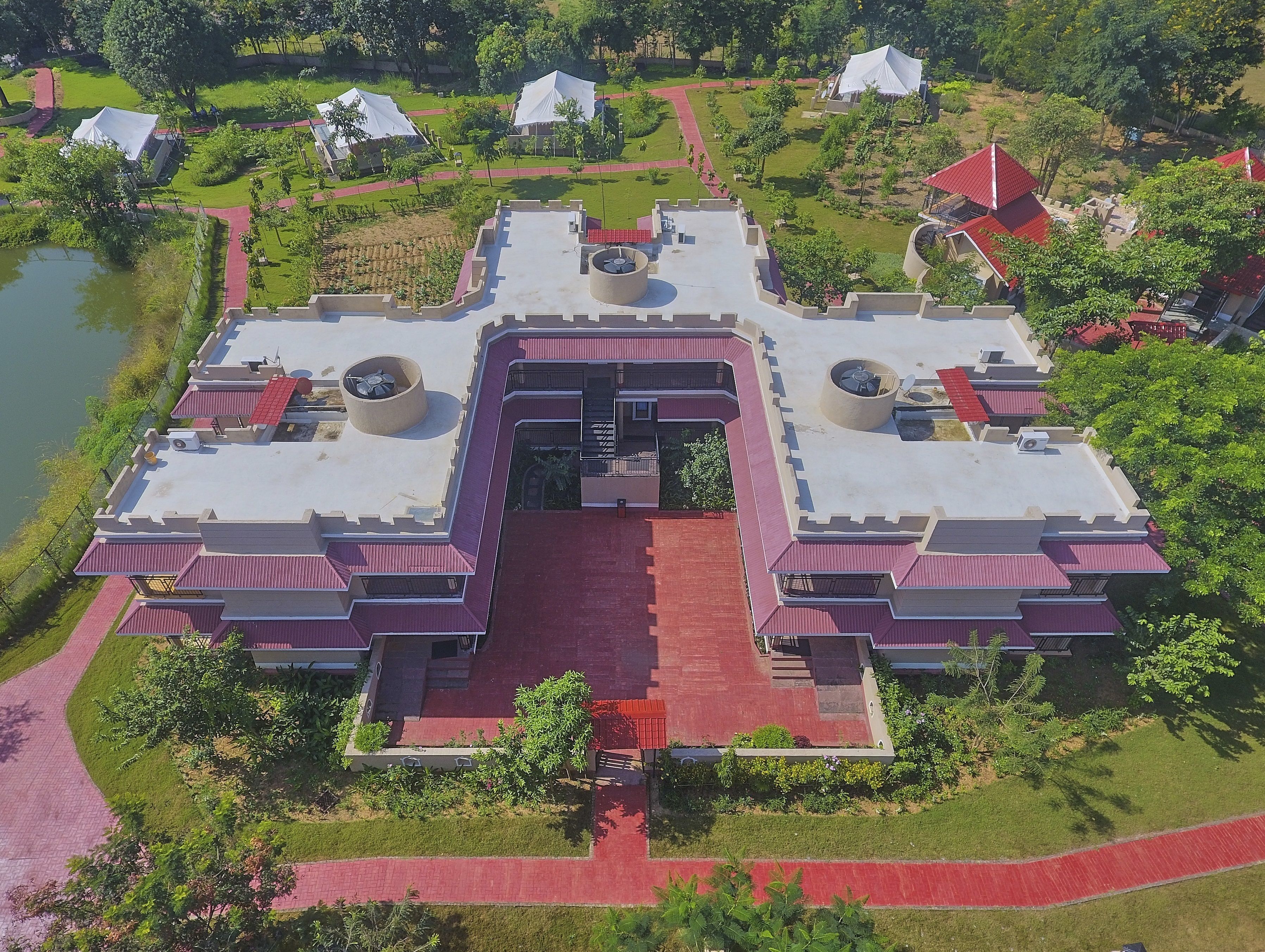 A large, modern building with a central courtyard, surrounded by greenery and a body of water.