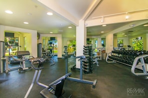 Une salle de sport équipée de machines de cardio, de matériel de musculation et de miroirs.