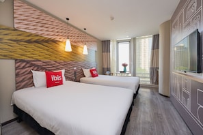 Habitación de hotel con dos camas, un televisor y un ventanal con cortinas.