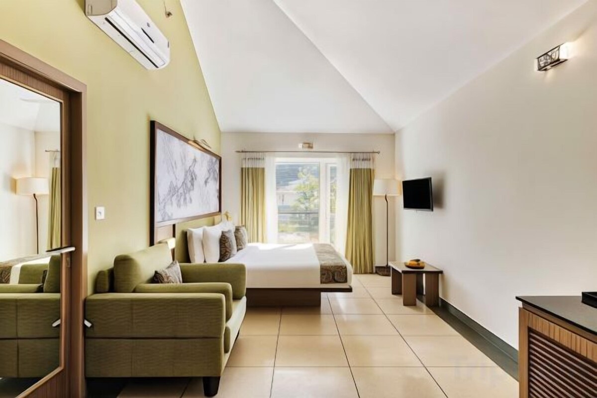 A hotel room with a bed, a sofa, a TV, and a desk.