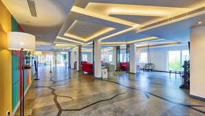 A spacious lobby with a modern design, featuring a large seating area with red sofas, a reception desk, and a large floor lamp. - Sterling Wayanad (Sulthan Bathery)