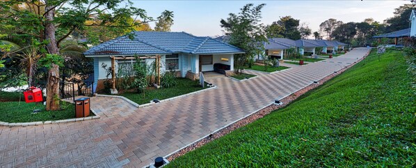 Una hilera de casas de campo con techo azul, un paseo pavimentado y céspedes verdes.
