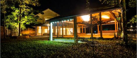 A well-lit building with a covered outdoor area, surrounded by trees.