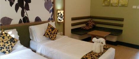 A hotel room with two beds, a bench, and a small table.