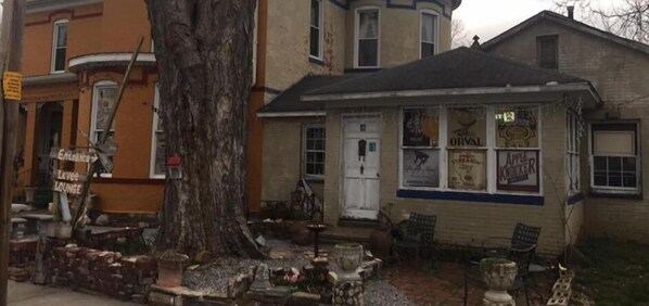 A building with a large tree in front, a sign for 'Orval Krueger', and outdoor seating. - Riverview Mansion Hotel (Golconda)