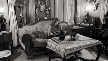 Une pièce au décor d’époque, avec un canapé, une table recouverte d’une nappe à motifs et une lampe décorative.