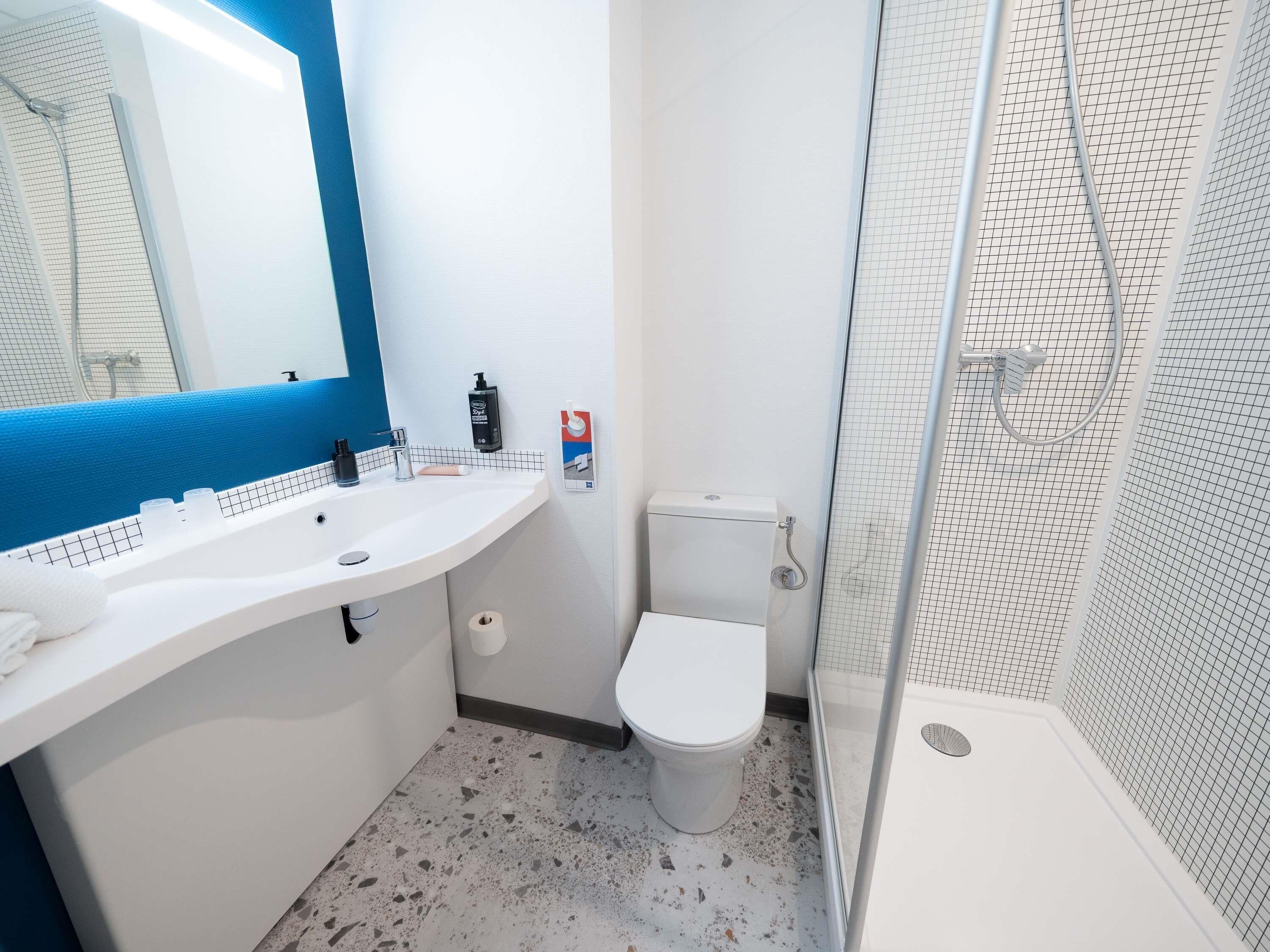 Une salle de bain avec un lavabo blanc, des toilettes et un espace douche.