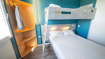 Uma cama beliche com encosto, um guarda-roupa de madeira com cabides e uma mala no chão.