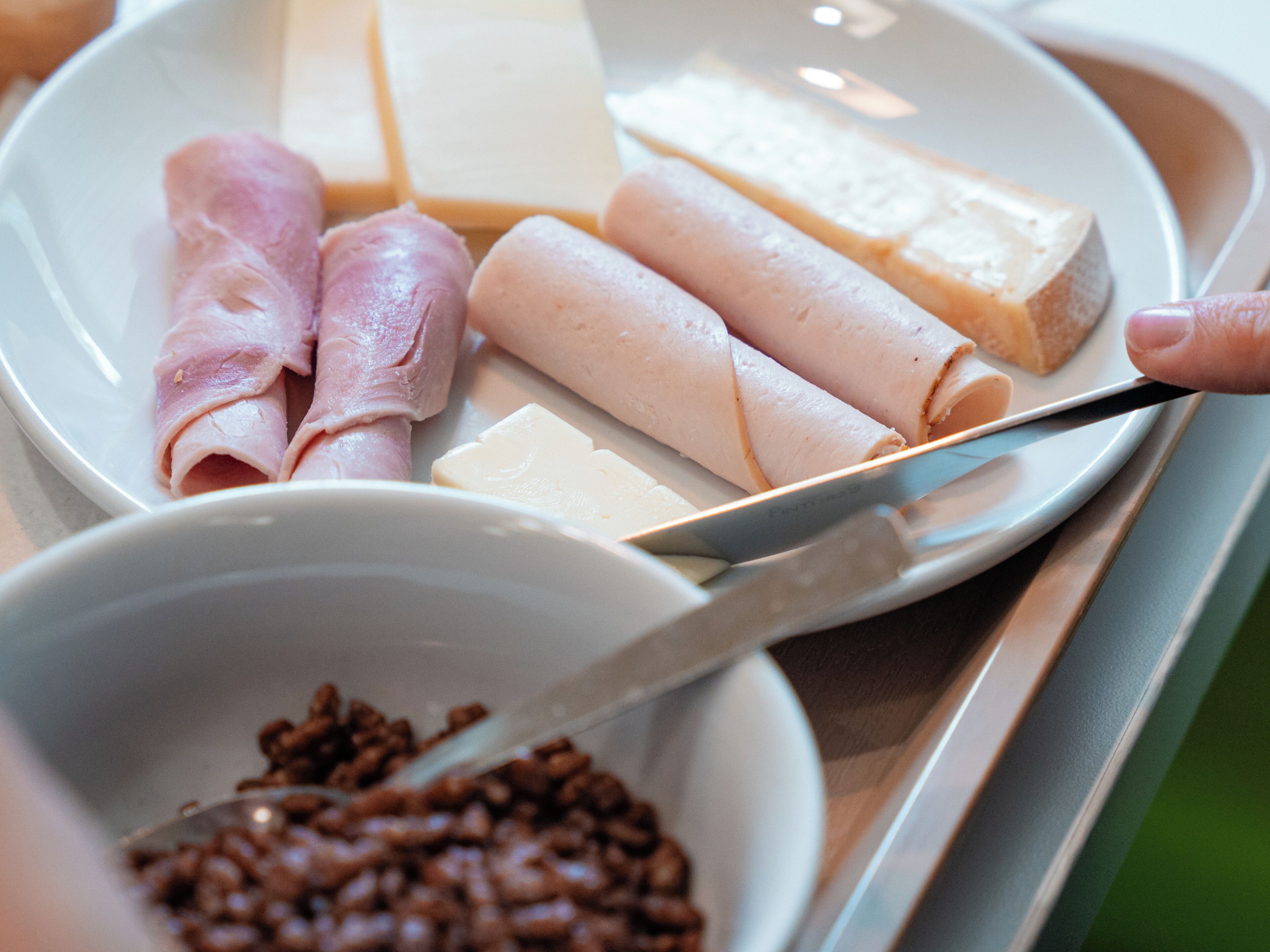 A plate with various food items including cheese, ham, and a bowl of coffee beans.