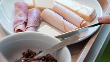 A plate with various food items including cheese, ham, and a bowl of coffee beans.