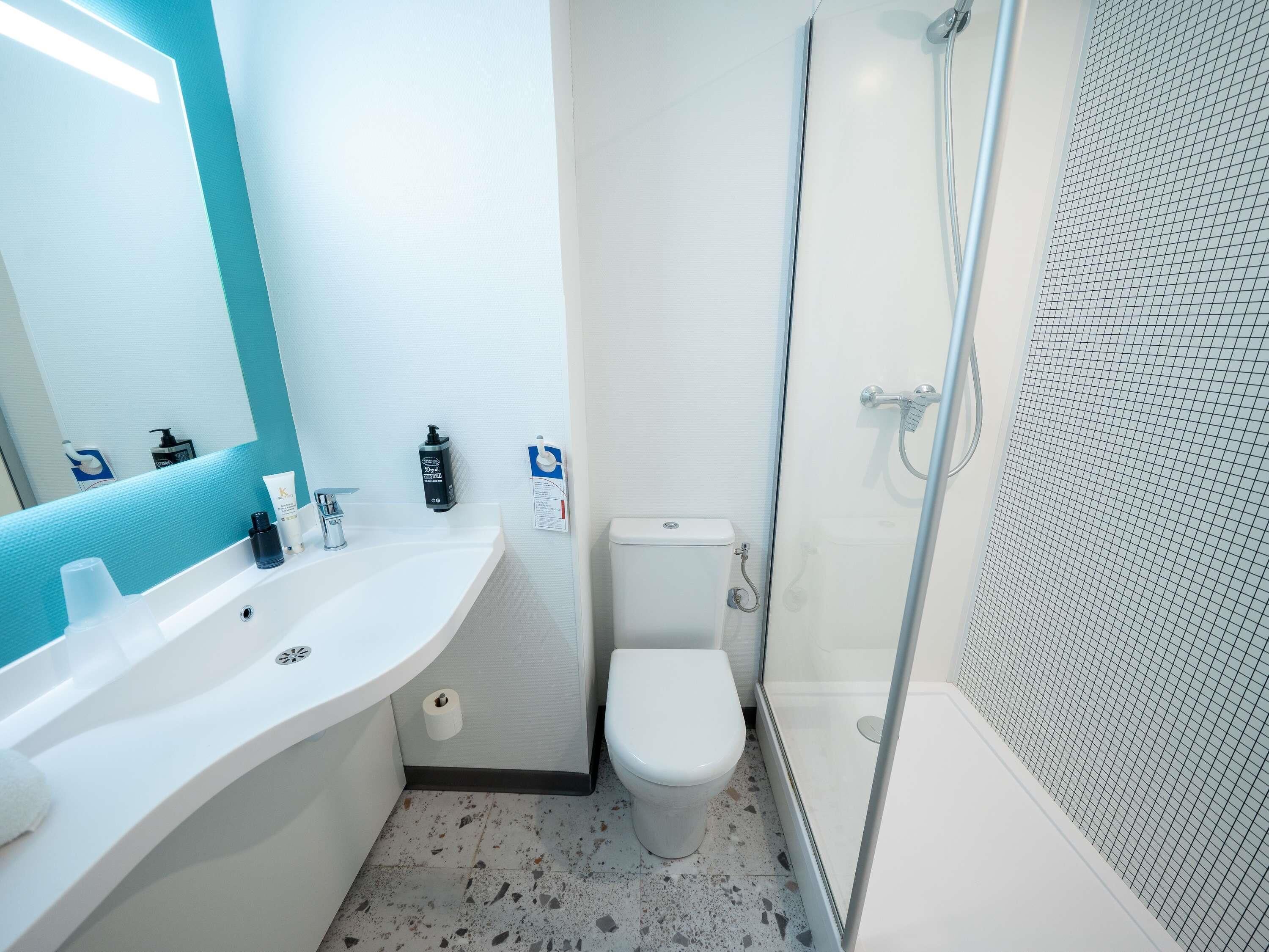 Un baño con lavamanos blanco, inodoro y ducha con mampara de vidrio.