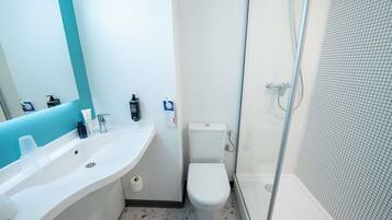 A bathroom with a white sink, a toilet, and a glass-enclosed shower.