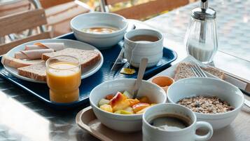 A breakfast tray with toast, fruit, cereal, coffee, and juice on a table outdoors.