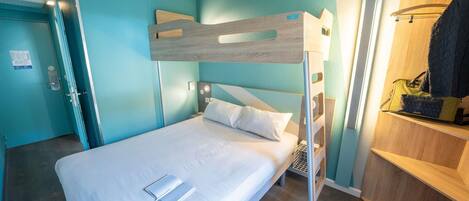 Una cama litera en una habitación con paredes color turquesa, cabecera de madera, mesita de noche y una bolsa colgada.