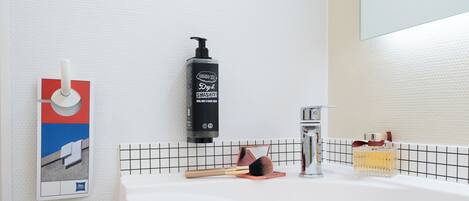 A bathroom with a white sink, a black soap dispenser, a mirror, and a hand towel rack.