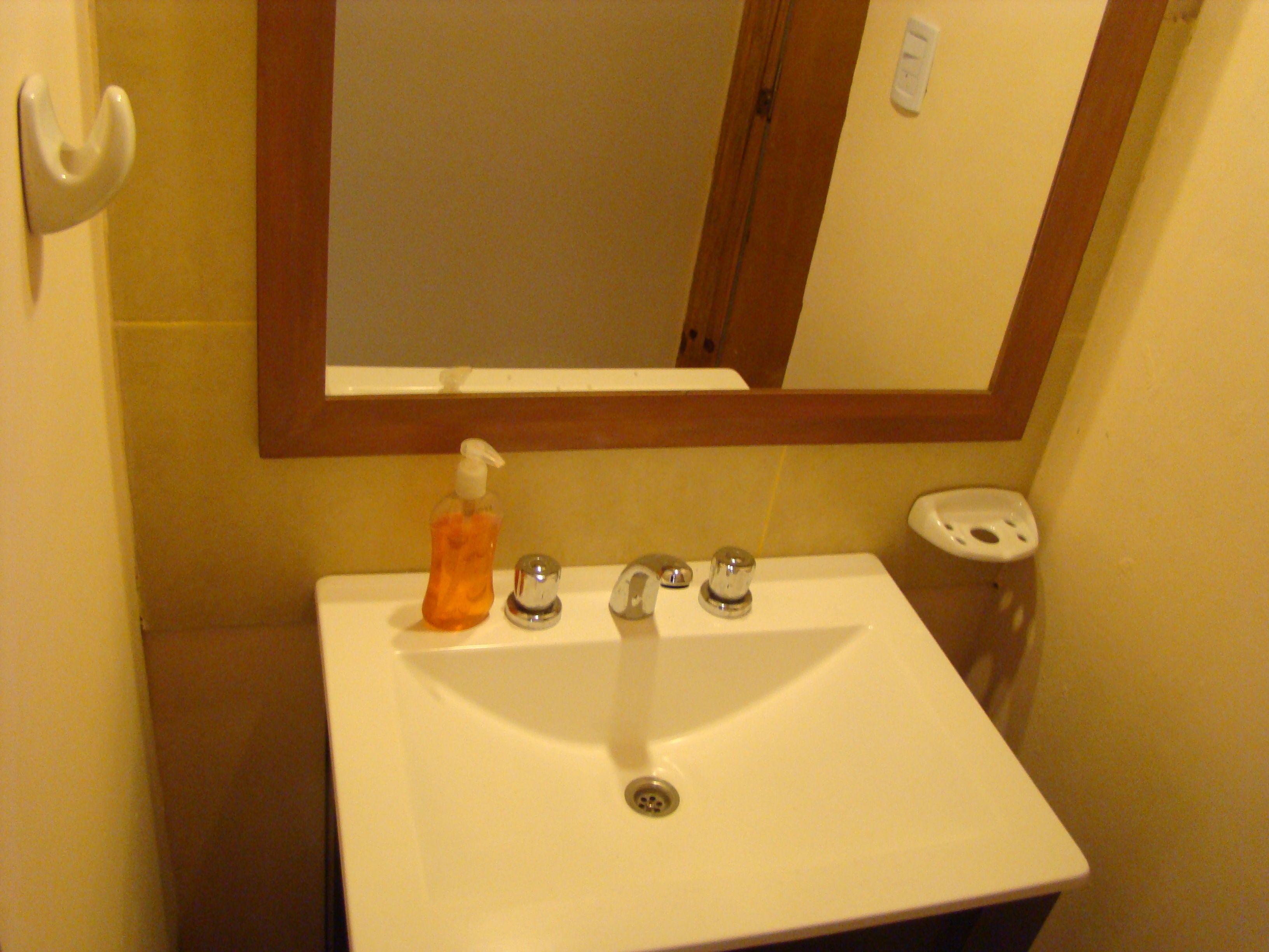 Une salle de bain avec un lavabo blanc, un miroir et un distributeur de savon.