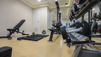 Une salle de sport équipée de matériel d’exercice, d’un banc et d’un miroir.