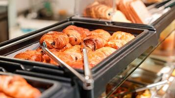 Un buffet con diversi prodotti da forno, tra cui croissant e pasticcini.
