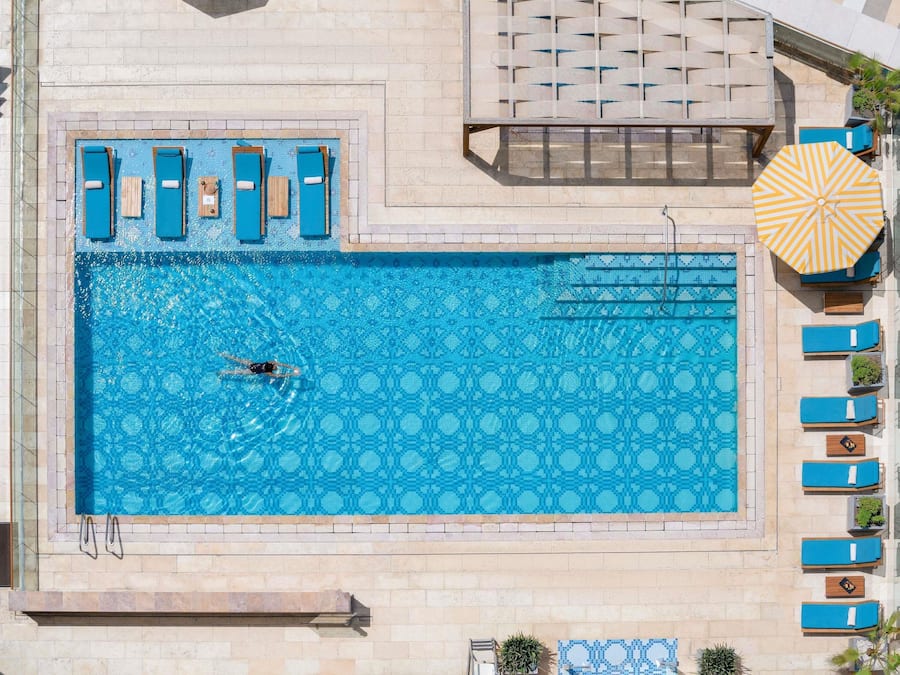 Una piscina al aire libre, sombrillas, sillones reclinables de piscina