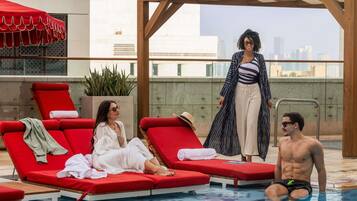 Una piscina al aire libre, sombrillas, sillones reclinables de piscina