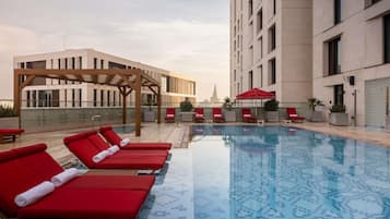 Een buitenzwembad, parasols bij het zwembad en ligstoelen