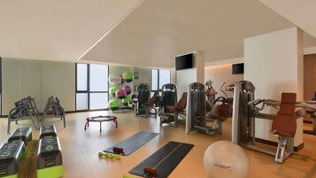 Une salle de sport équipée de matériel d’exercice, de tapis et d’un grand miroir.