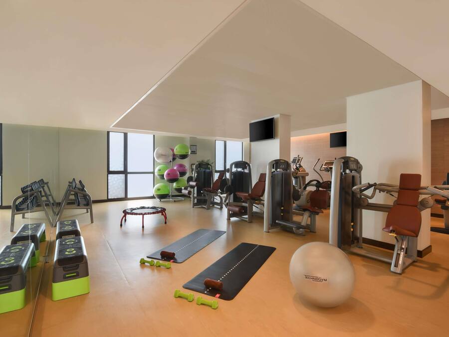 Une salle de sport équipée de matériel d’exercice, de tapis et d’un grand miroir.