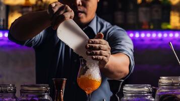 Un barman verse une boisson dans un verre rempli de glaçons.