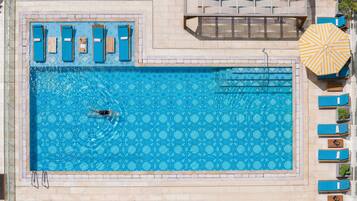 Alberca al aire libre, sombrillas en la alberca y camastros