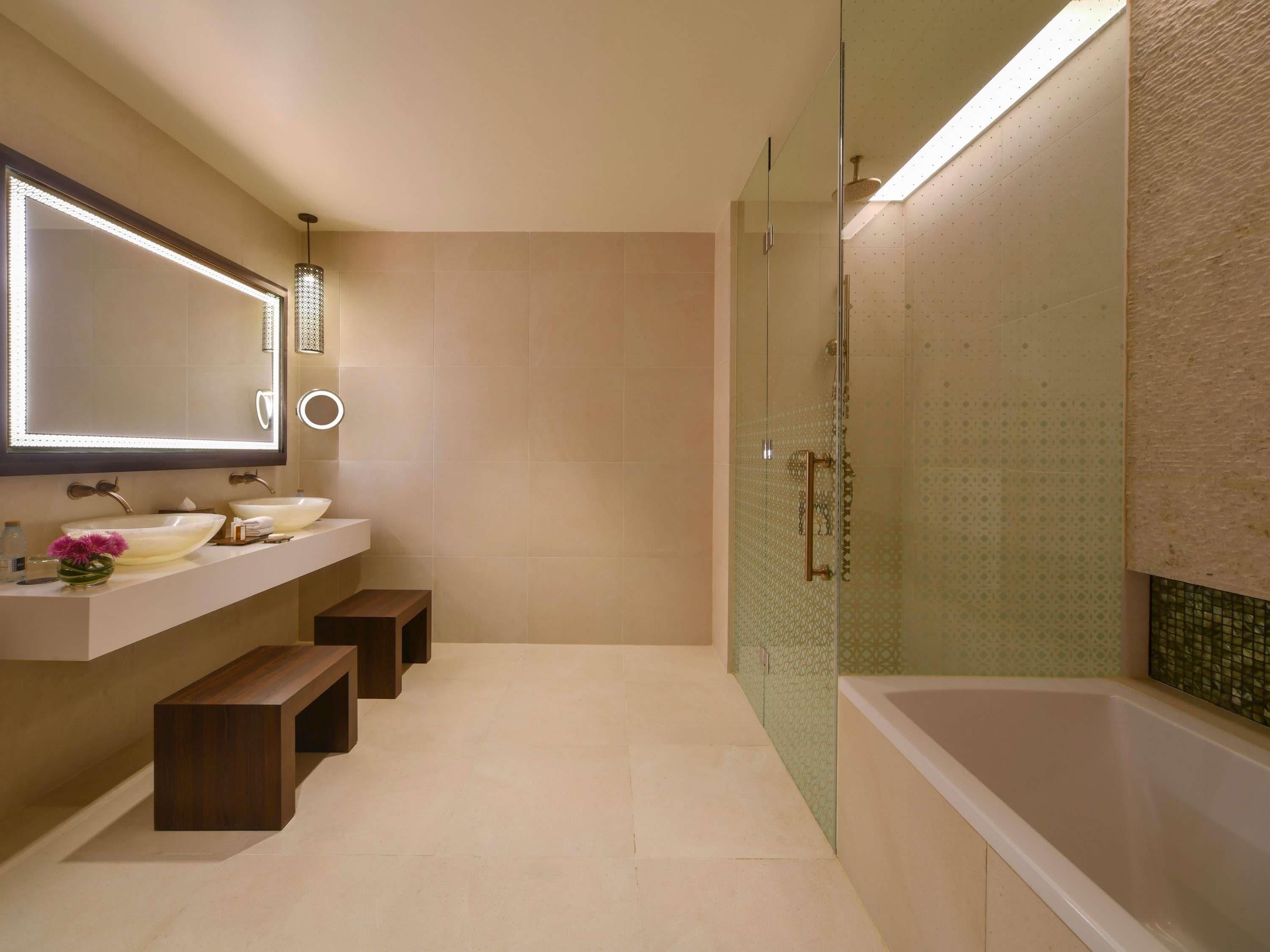 Un baño moderno con dos lavamanos, un espejo grande y una ducha con cerramiento de vidrio.