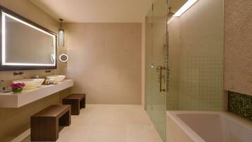 Un baño moderno con dos lavamanos, un espejo grande y una ducha con cerramiento de vidrio.