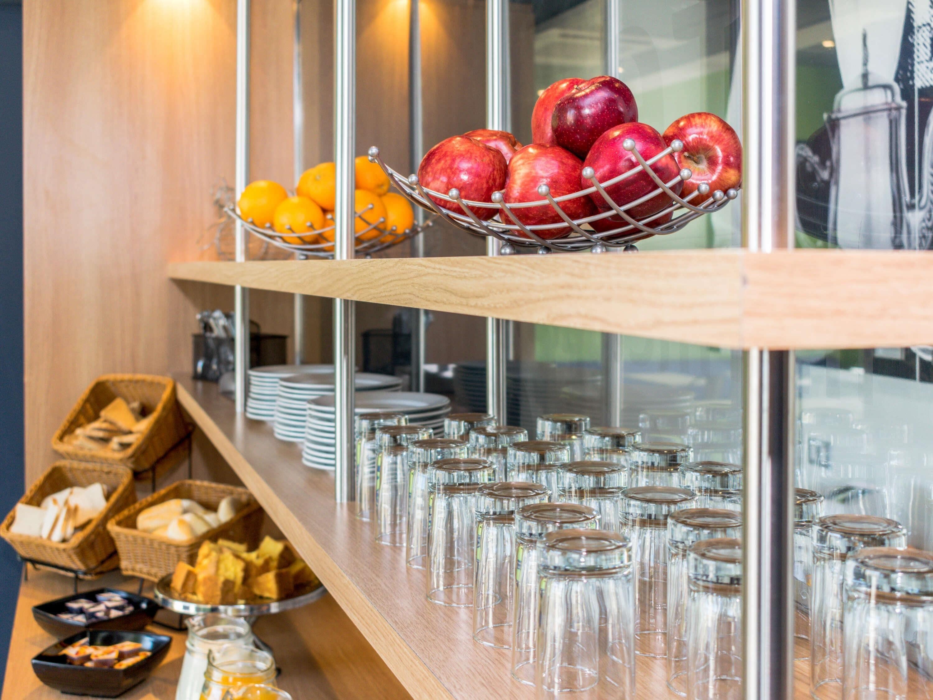 A buffet setup with fruits, bread, and glassware.