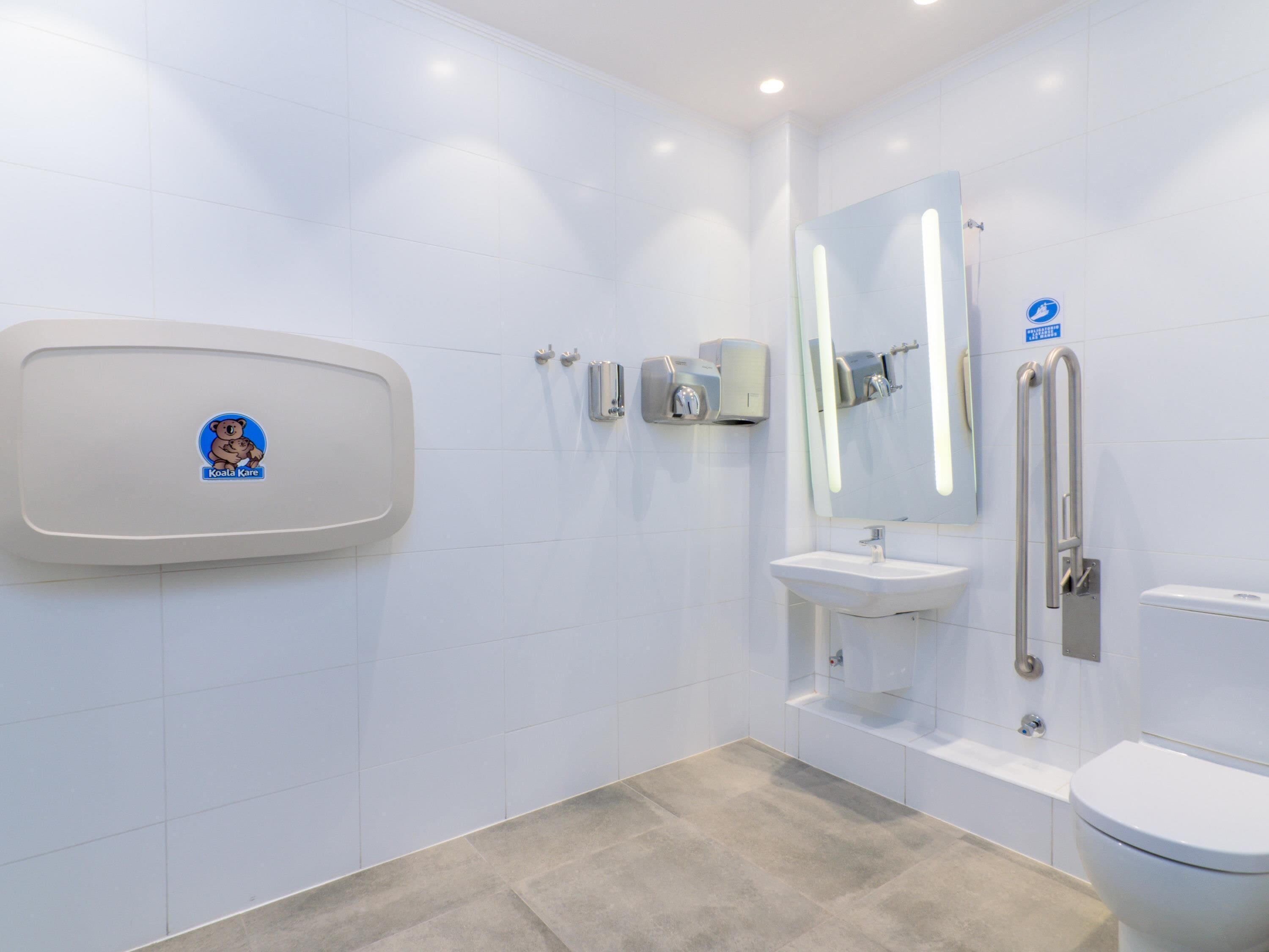 Ein modernes Badezimmer mit Toilette, Waschbecken und Handtrockner.