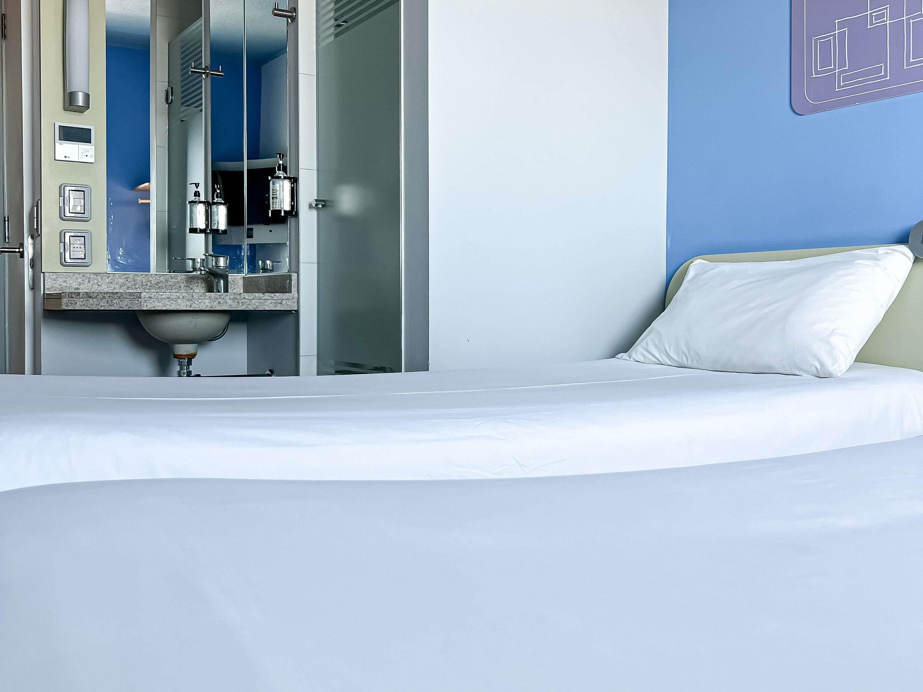 A hotel room with a bed, a bathroom with a sink, and a mirror.