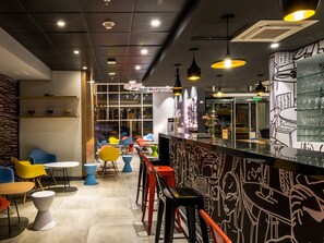A modern interior with a bar area, colorful chairs, and a decorative wall. - ibis Iquique (Iquique)
