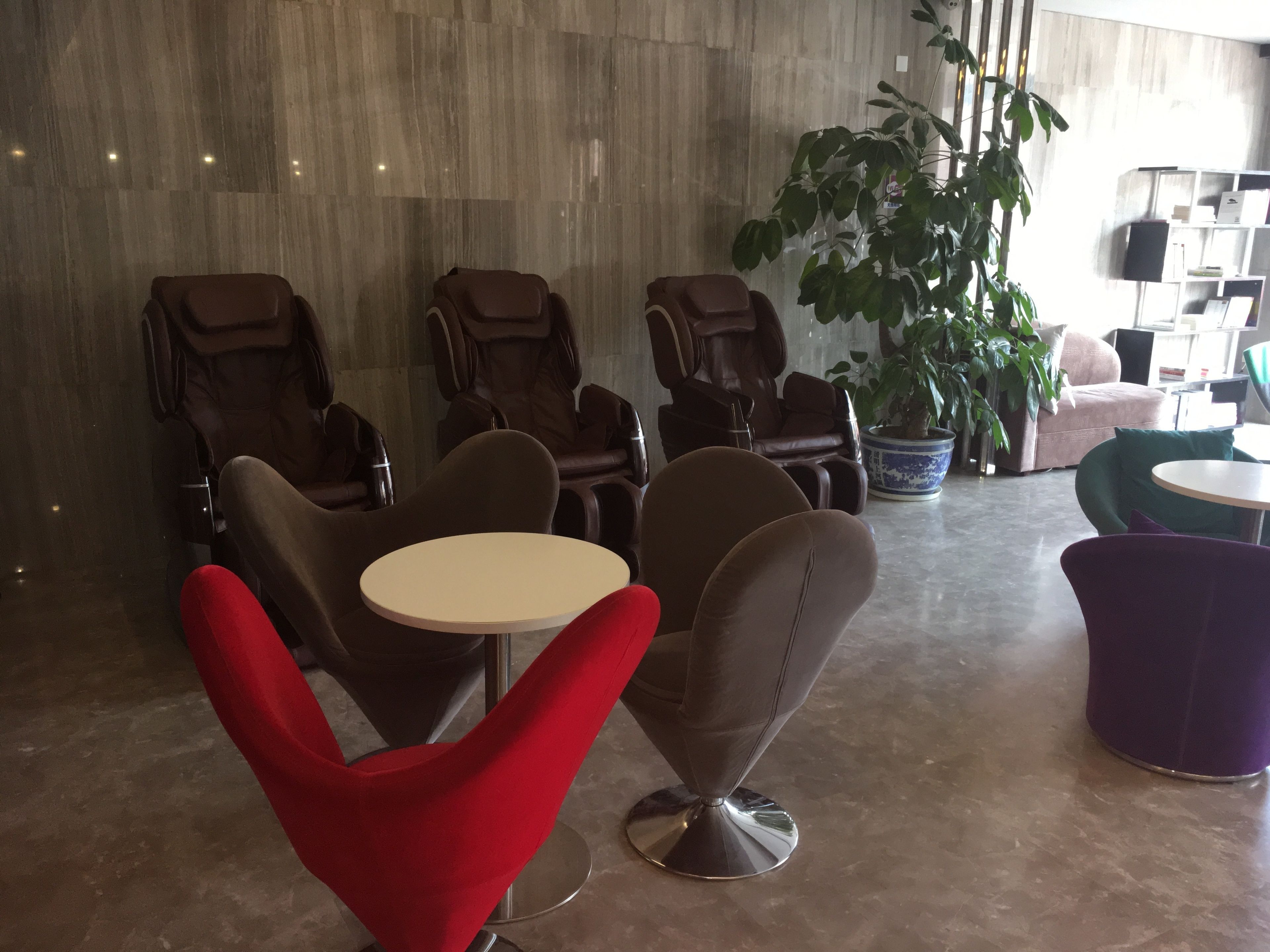 Un espace détente moderne comprenant plusieurs fauteuils de massage, une table ronde et une plante en pot.