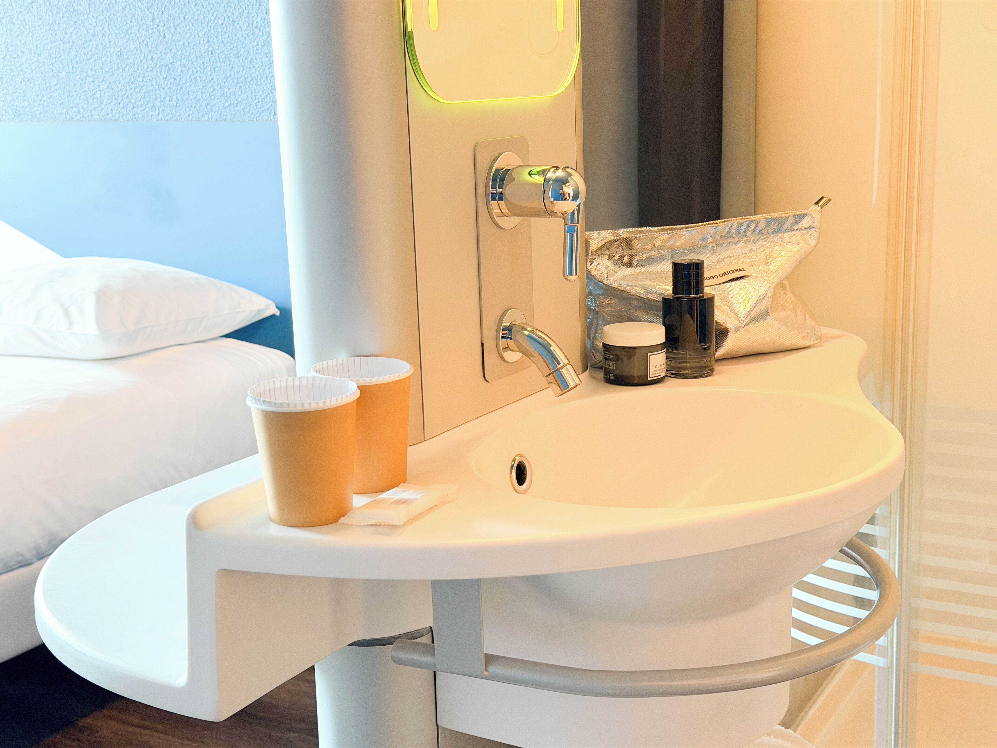 Un baño de hotel con lavabo, espejo y artículos de aseo.