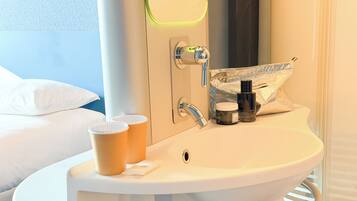 Une salle de bain d’hôtel équipée d’un lavabo, d’un miroir et d’articles de toilette.