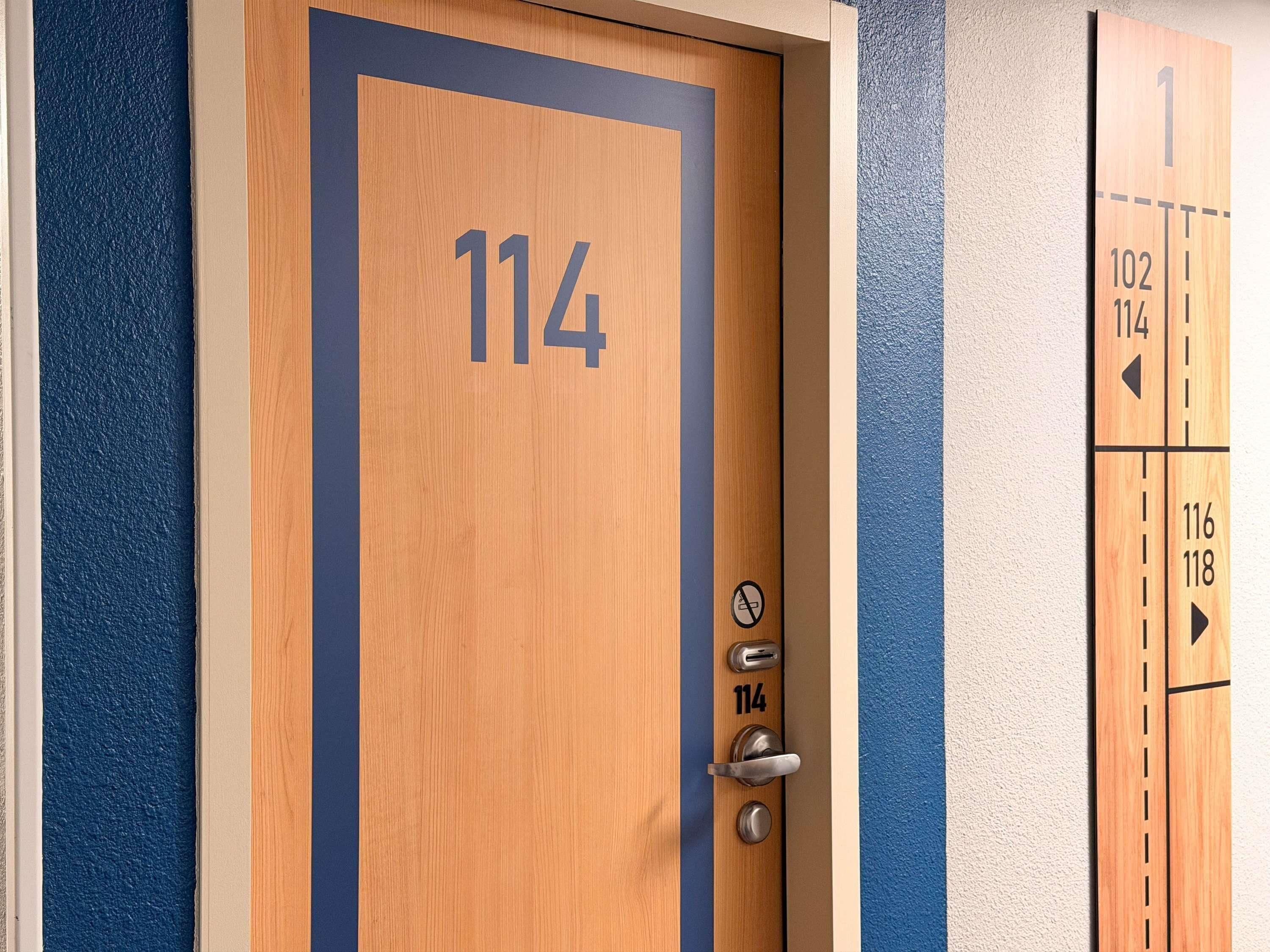 Una porta in legno con il numero 114, una serratura e una maniglia.