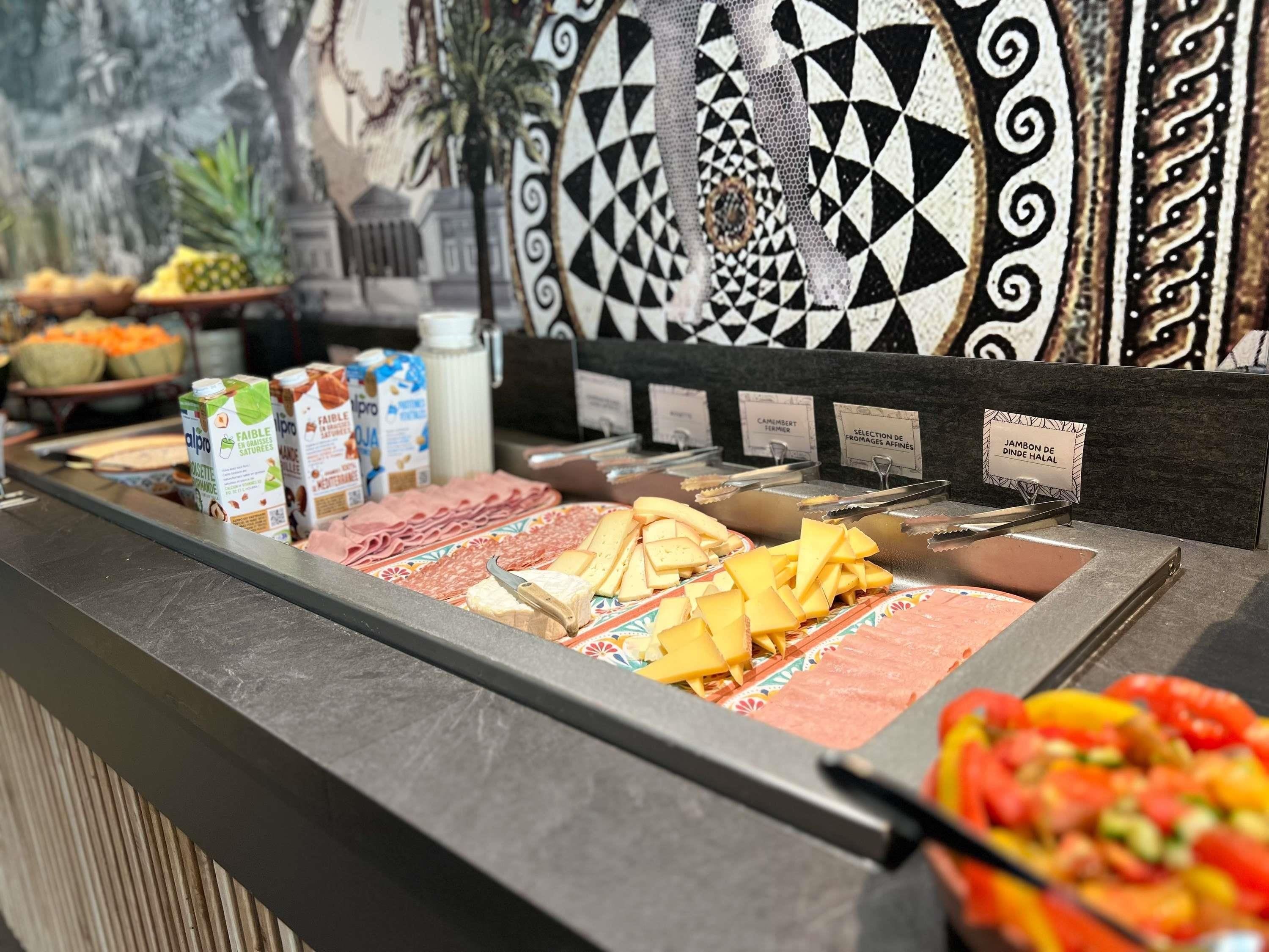 A buffet with various food items including meats, cheeses, and fruits.