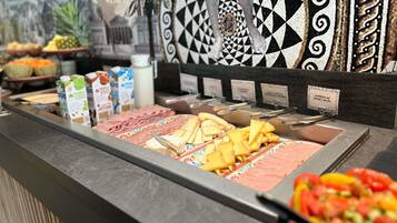 A buffet with various food items including meats, cheeses, and fruits.