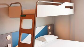 A bunk bed with a ladder, a bedside table, a wall socket, and a light switch.