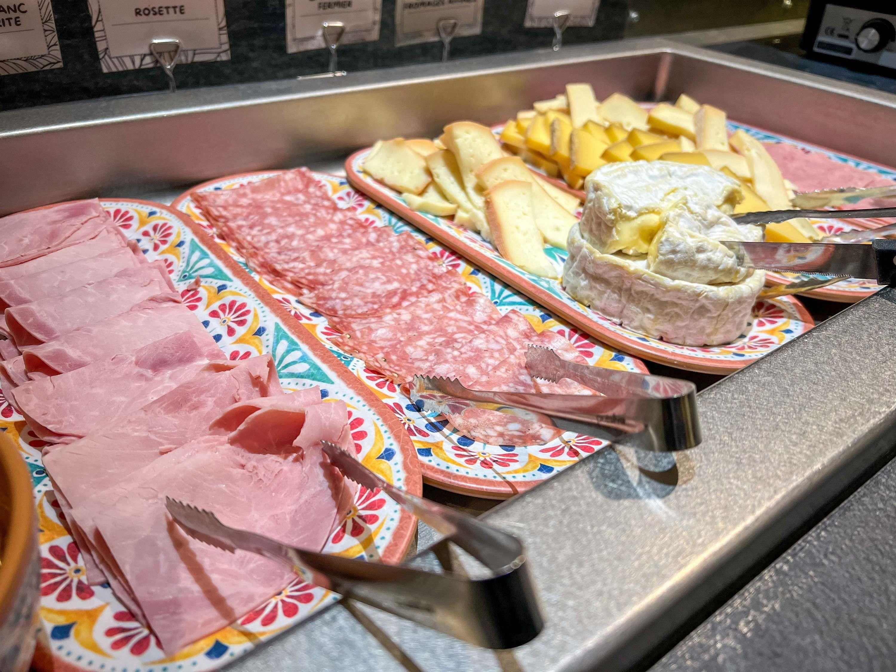 En skærebræt med forskellige slags pålæg, oste og brød.