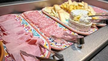 En skærebræt med forskellige slags pålæg, oste og brød.