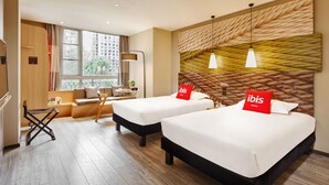 Habitación de hotel con dos camas, un sofá, un escritorio y un ventanal grande.