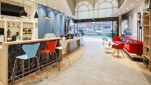 Un área de bar moderna con una barra curva, taburetes y una zona de estar con un sofá rojo y sillas.