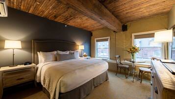 A bedroom with a large bed, bedside lamps, a dresser, and a window with a view of buildings.